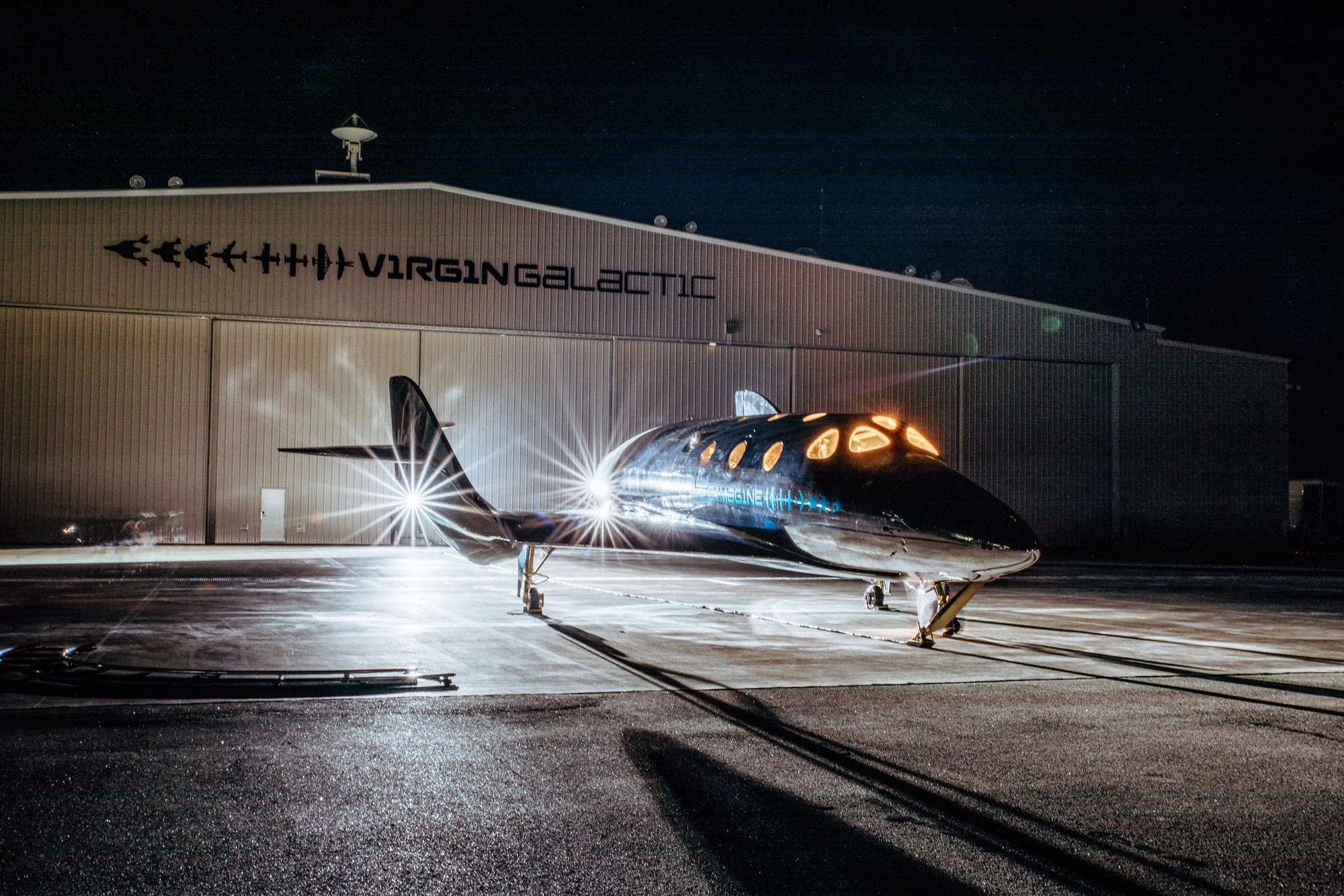 VSS Imagine with hangar in the background at night. IS Virgin Galactic.