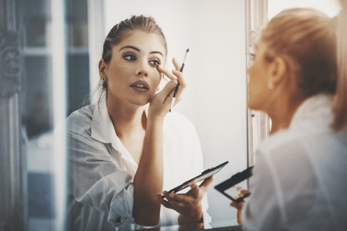 Person applying makeup while looking in the mirror.