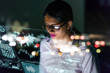 A person looking at graphs and charts on a futuristic see-through interface
