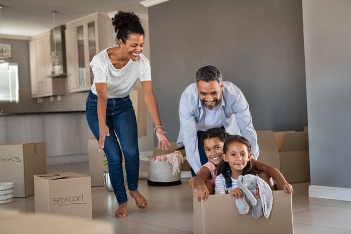 Adults and children in a home with boxes.