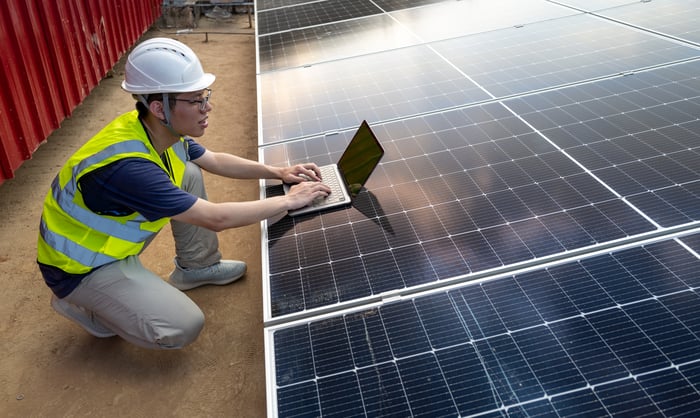 Person using a laptop on top of a solar panel.
