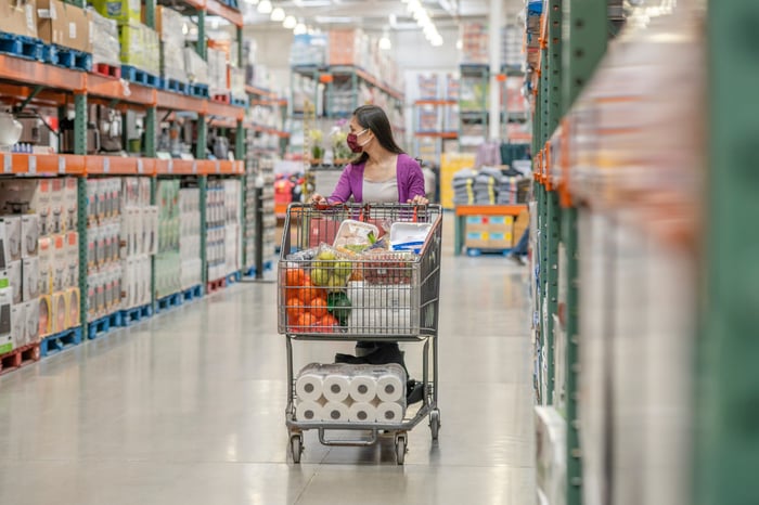A person pushing a full cart in a warehouse club setting.