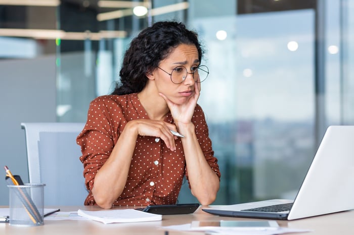 A person at a laptop looking unhappy.