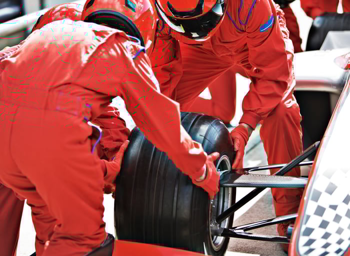 Two workers changing the tire of a race car.