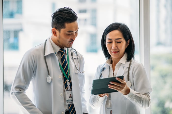 Two doctors discuss something in a hospital setting.