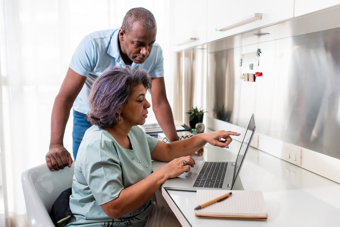 Two people with serious expressions looking at a laptop.
