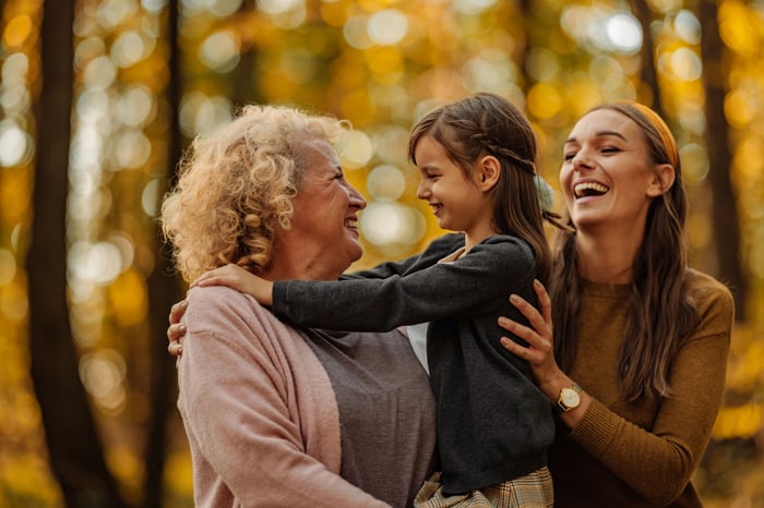 Older adult, younger adult, and child walking in the woods. 