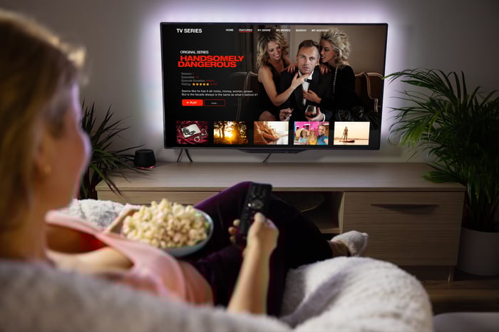 A person on couch with popcorn watching streaming TV. 
