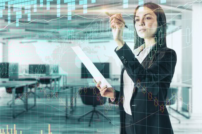 Stock analyst looking at chart of a stock projected on a glass wall.