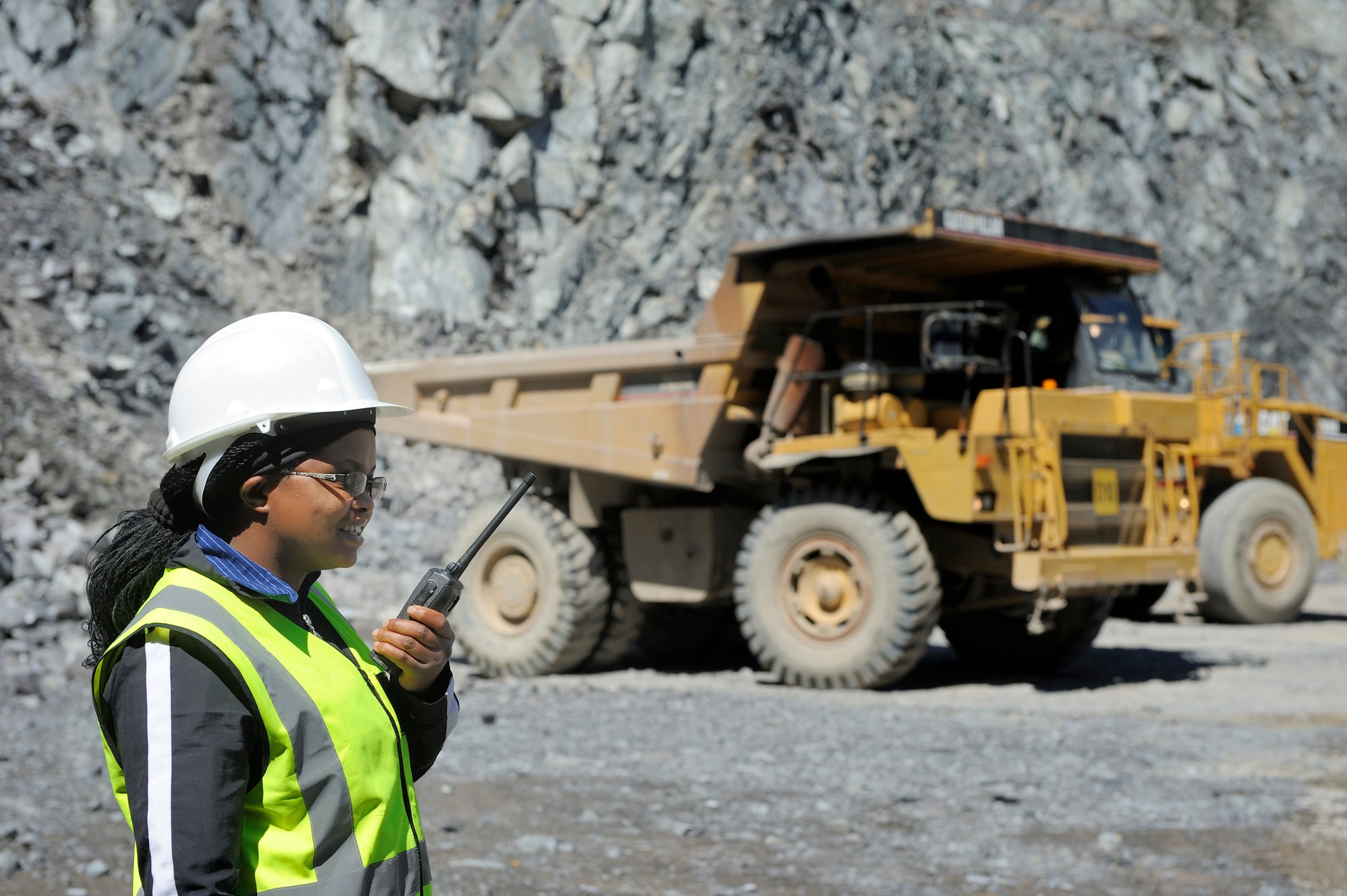 21_05_18 A person in protective gear talking on a communications device with a dump truck in the background _GettyImages-155380861