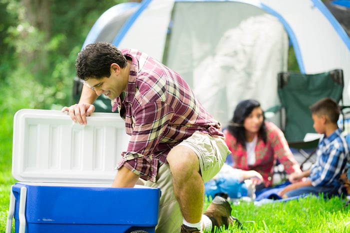 Person reaching into a cooler while camping.