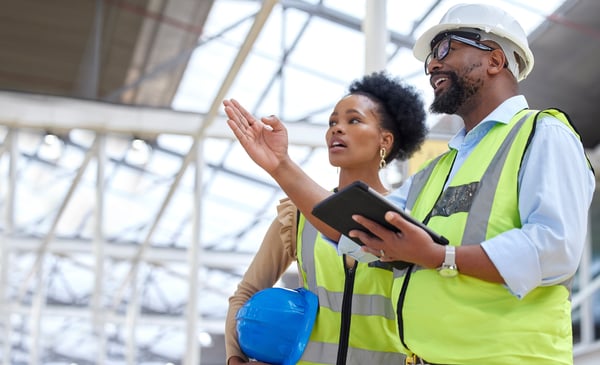 A construction contractor talks with a customer while holding a tablet computer.