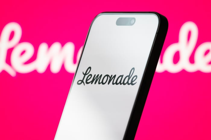 A smartphone with a "Lemonade" screen lit up on it is held against the company's pink-and-white logo in the background.
