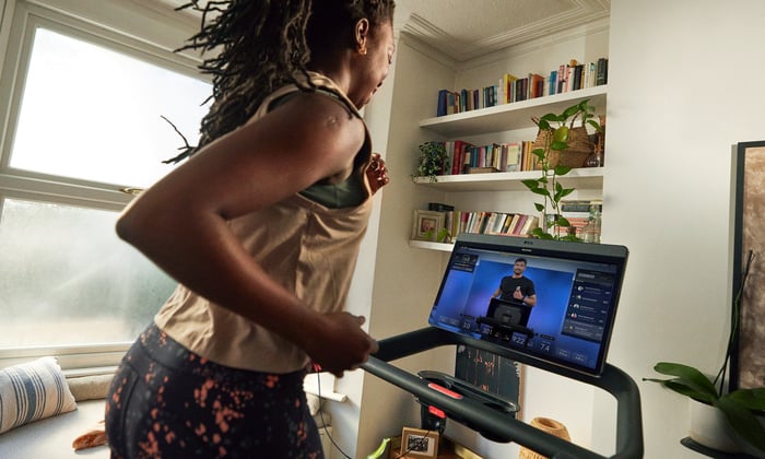 Person using Peloton treadmill while Peloton instructor is in view on screen.