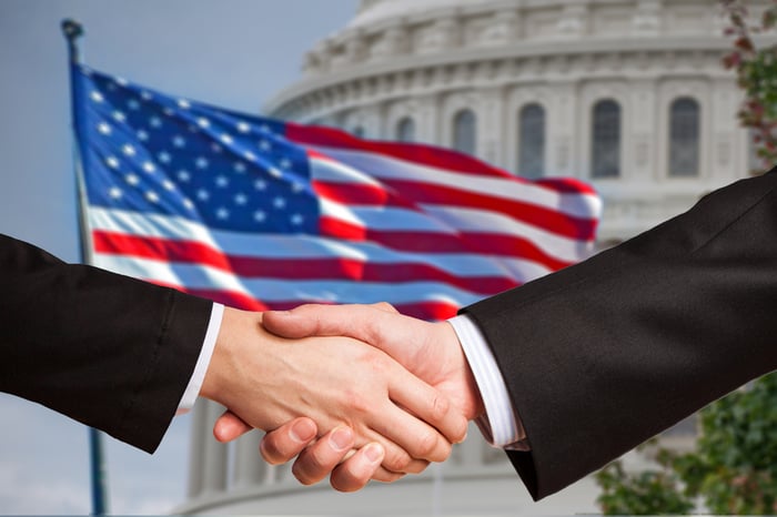 handshake in front of American flag and capitol building.