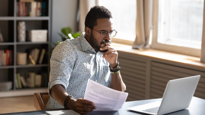 An investor looks pensively at a laptop in an office.