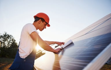 22_03_21 A person looking at papers on a solar panel _GettyImages-1304698521