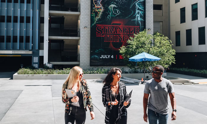 People walking towards camera with Stranger Things Netflix ad behind them.