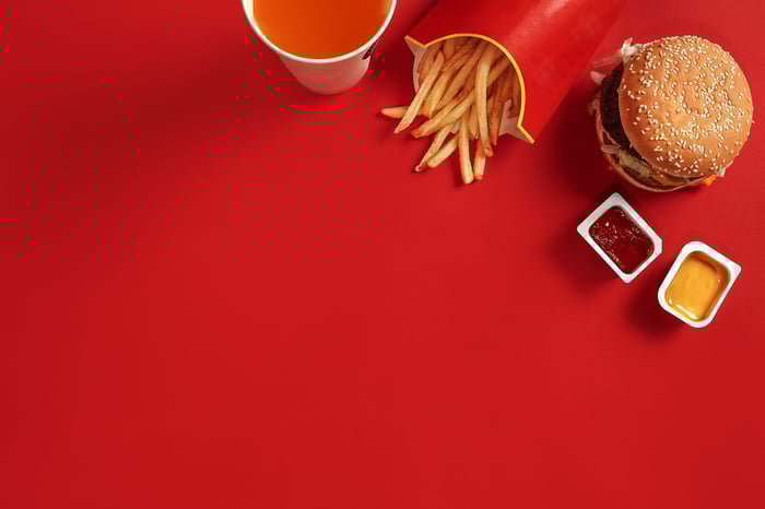French fries, a hamburger, and a drink on a red table.