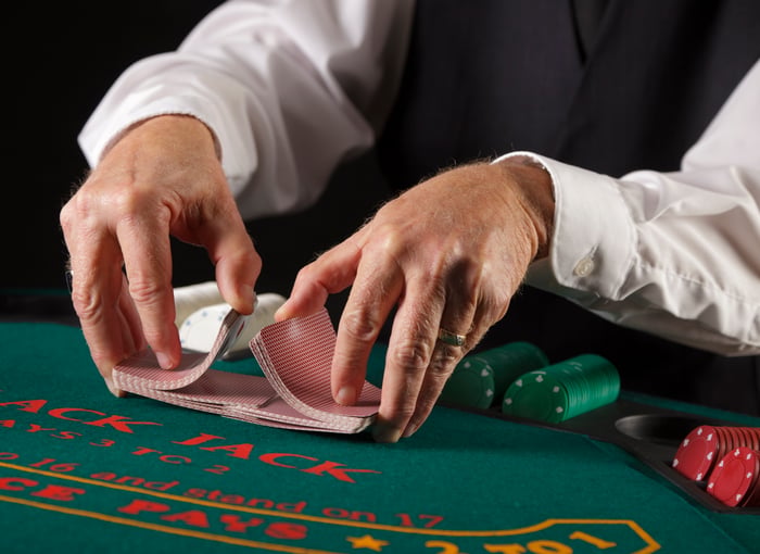 Hands of a dealer shuffling cards at a gambling table.