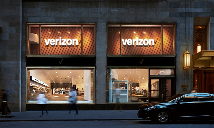 A Verizon store with a blurred image of people walking by.