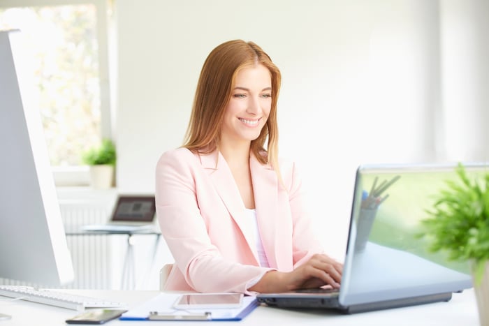 Professional working on a laptop while smiling.