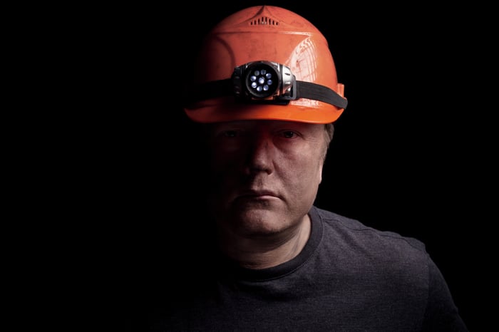 A miner in an orange hard hat with a light on it.