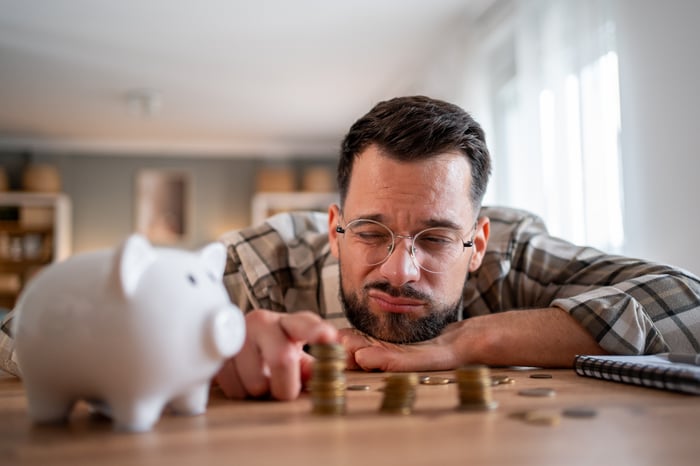 Someone stacking pennies next to a piggy bank.