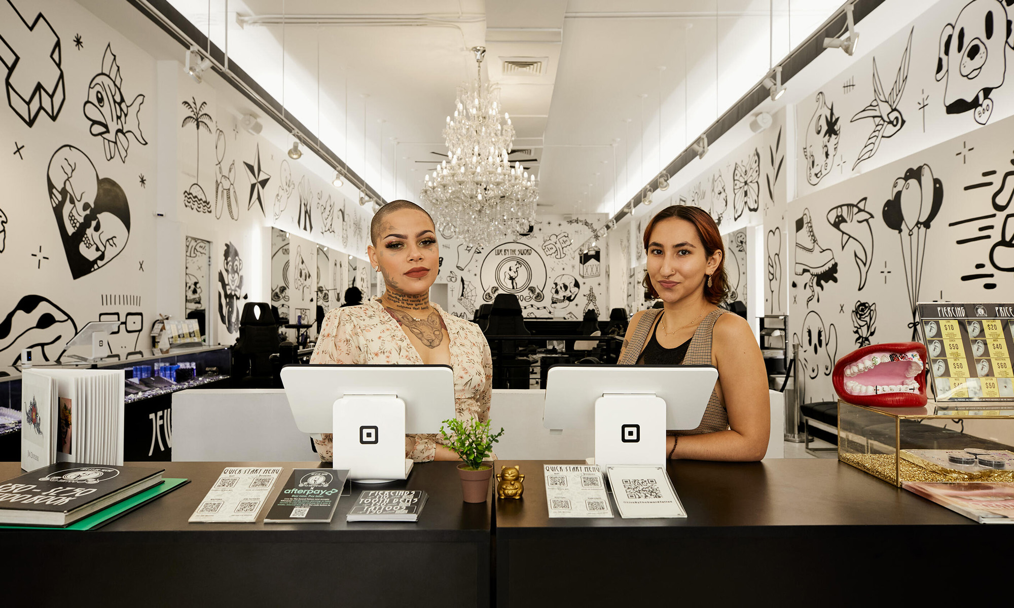 two people standing behind desk with two square block devices with square block logo_block