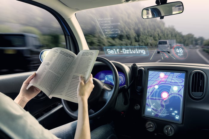 Person reading a book while sitting in a futuristic car.