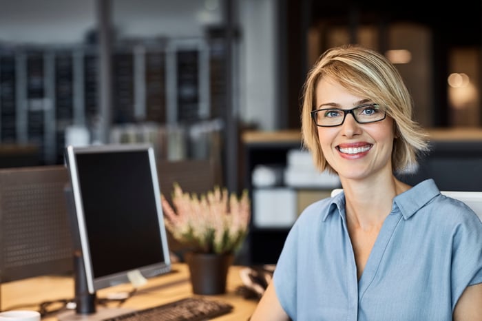A smiling person at a desk.