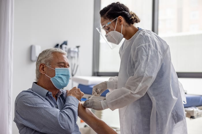 Nurse vaccinating a masked patient.