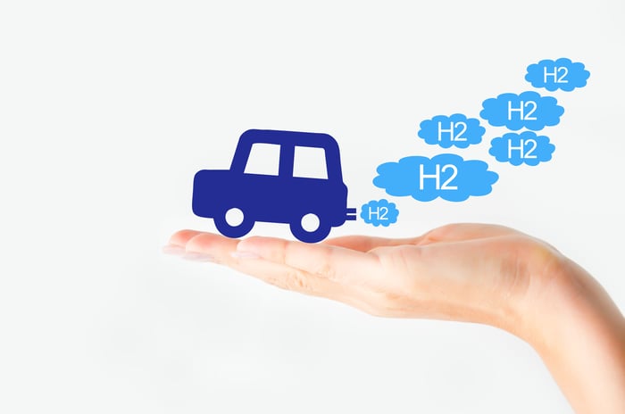 Hand holds out a fuel cell car putting out H2 bubbles as exhaust.