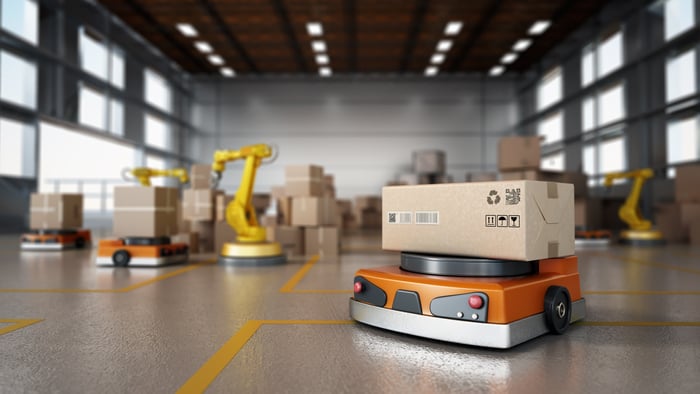 A robotics arm carrying a parcel at a warehouse.