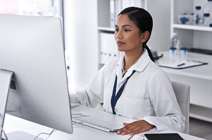 A medical professional at a desk looking at the computer. 
