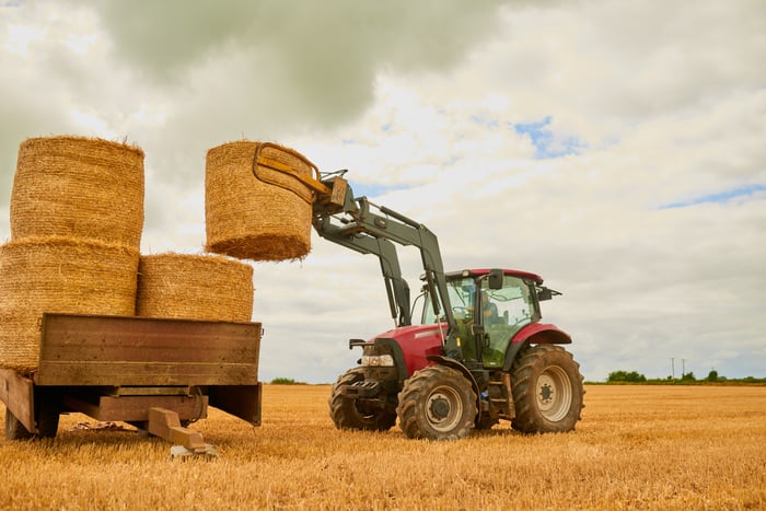 A tractor lifts a bale of hay.