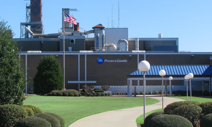 Procter & Gamble logo on the side of a building beside a nicely maintained lawn with shrubbery.