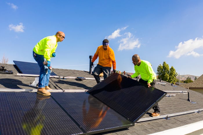 Roofers install solar panels on a house.