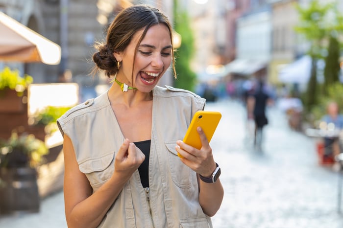 Young excited investor with yellow smartphone.