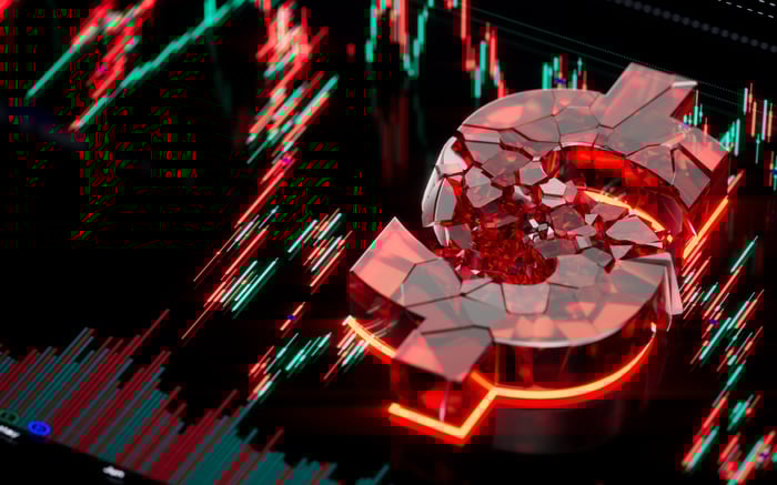 Chart lines going down over a dollar sign made of fracturing red glass.