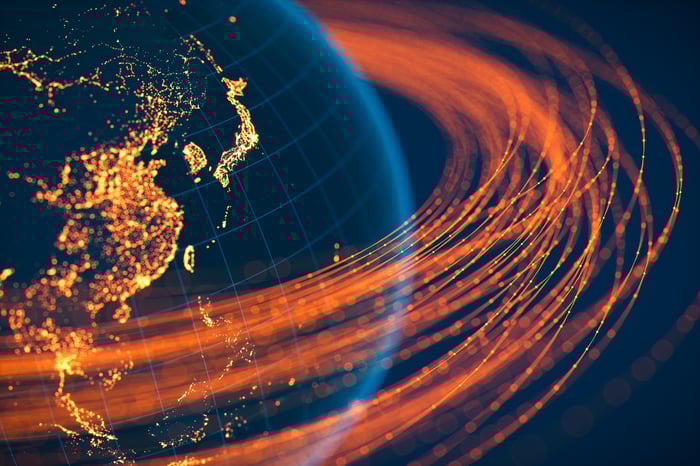 A bunch of satellites highlighted in orange orbiting around the earth. 