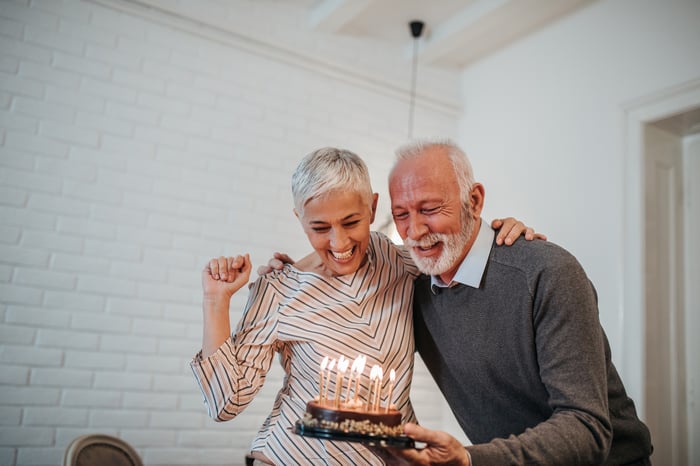 Two people standing over a cake with candles.