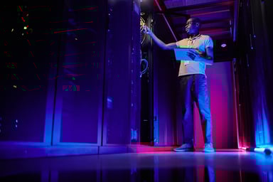 A system administrator setting up server network in a data center lit by neon light