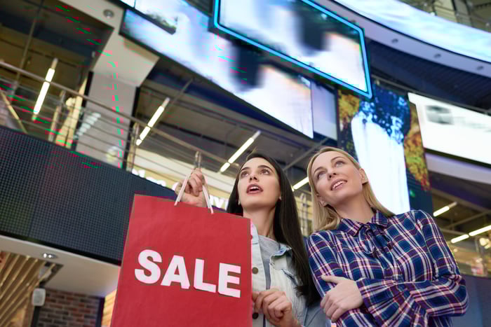 Two people holding a SALE bag as they shop.