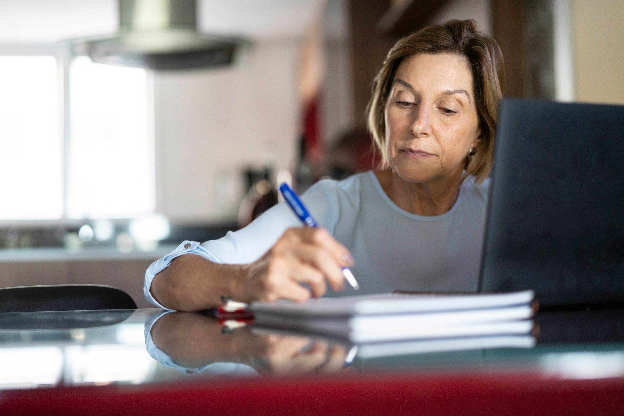 Older woman taking notes laptop GettyImages-1143057831