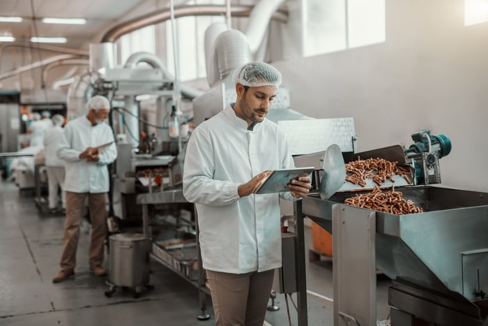 Person looking at a tablet in a food processing plant.