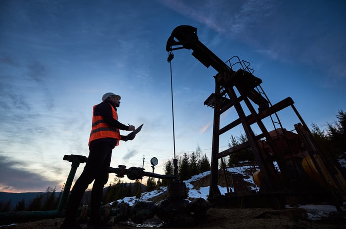 A person looking up at an oil pump.