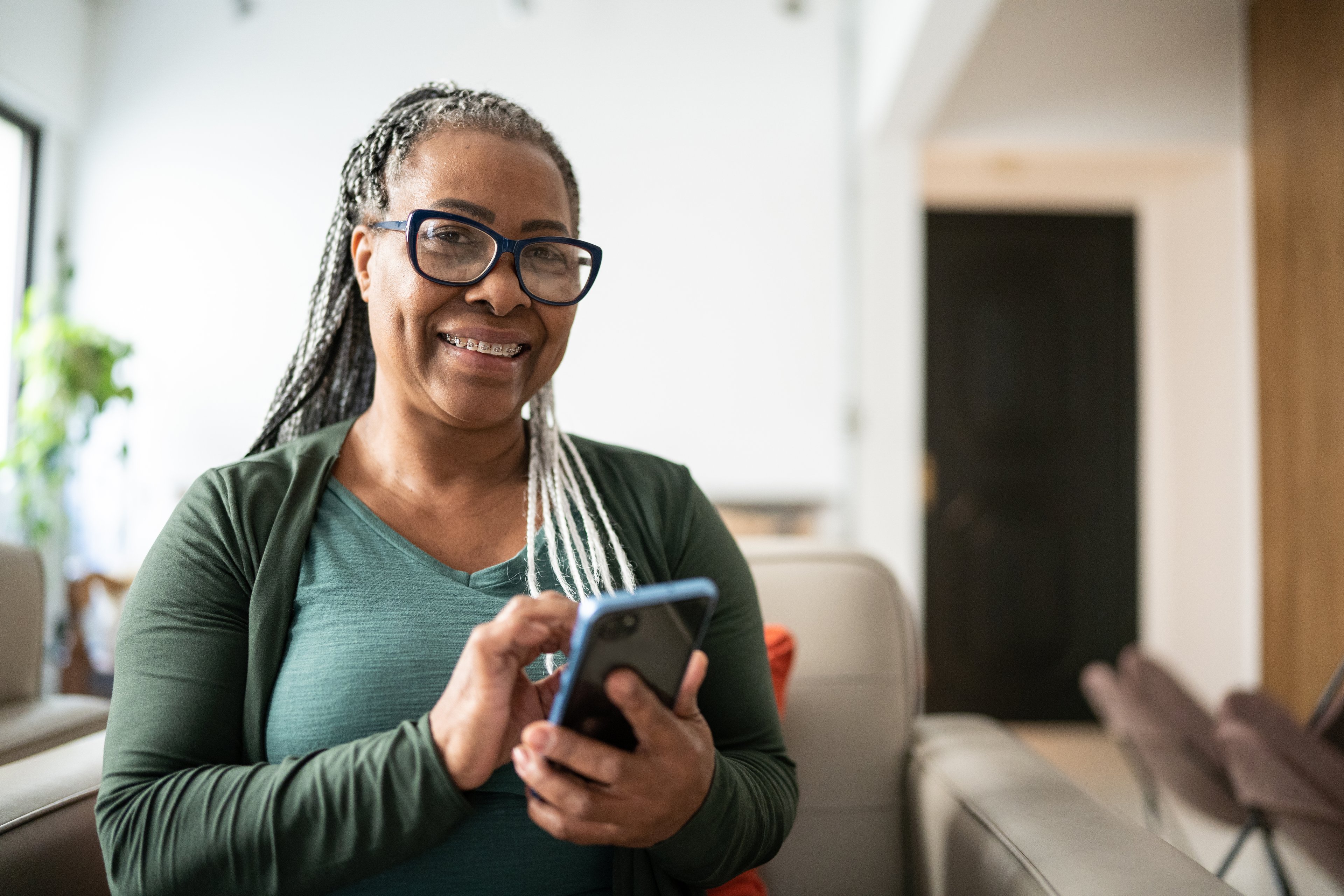 older woman smiling holding phone GettyImages-1356378445
