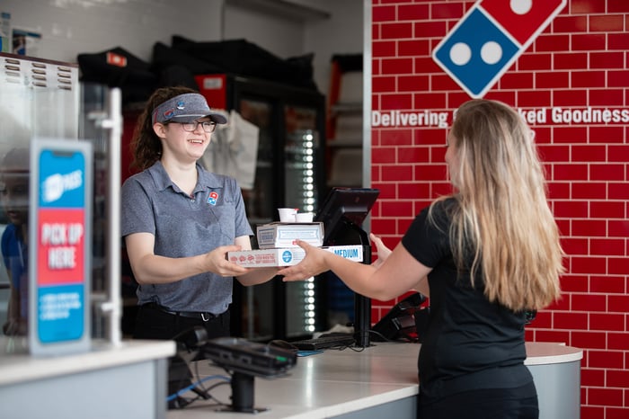 Domino's pizza service person giving a customer an order.