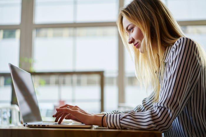 An investors types on a laptop in an office. 